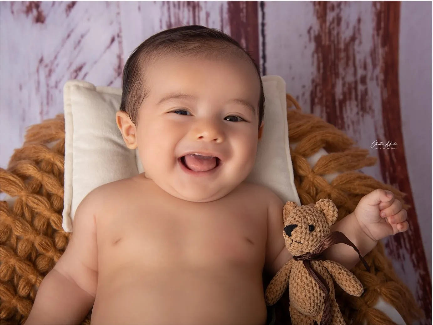 Bebé sonriente con oso de peluche en sesión de estudio