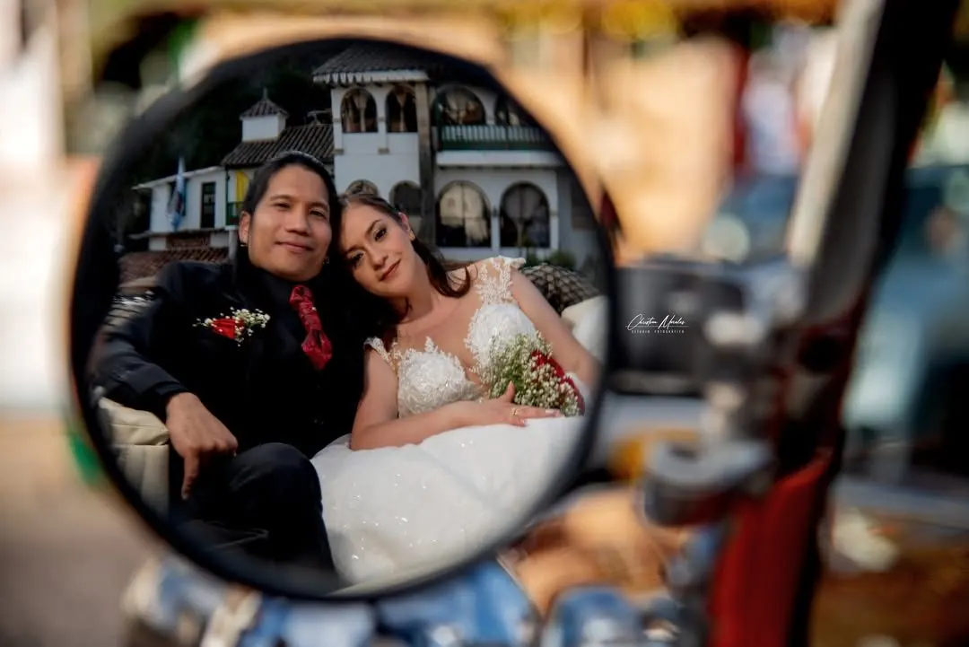 Novios reflejados en espejo de auto clásico